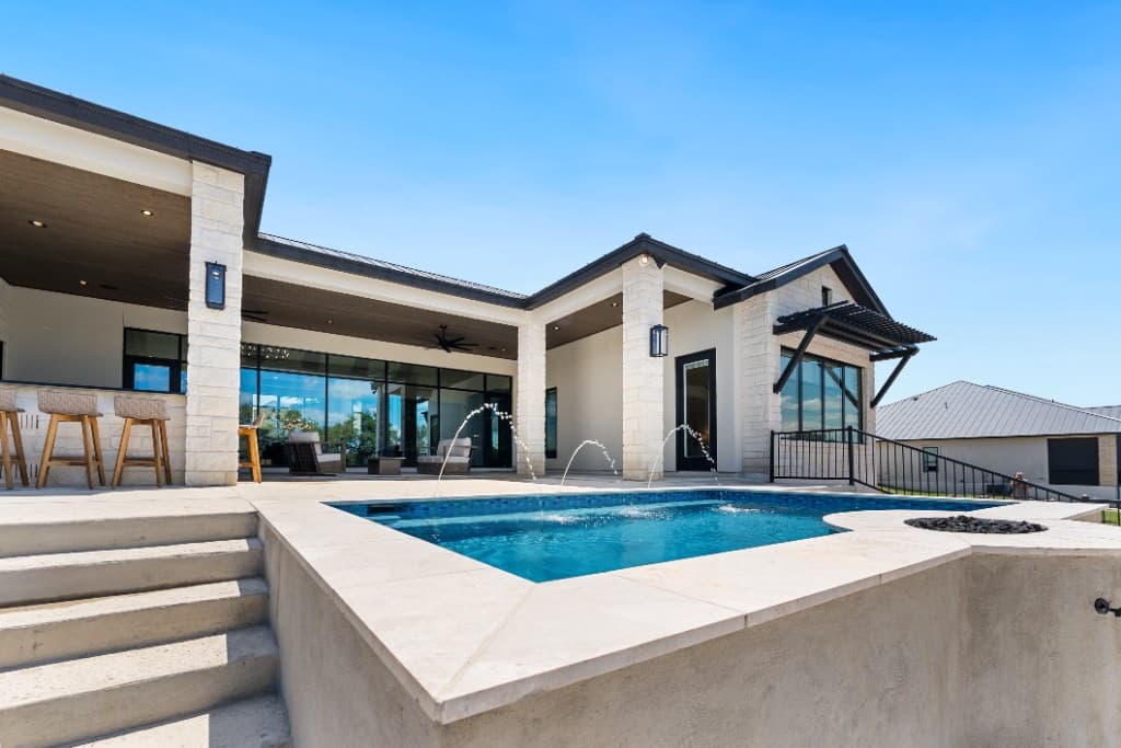 Elevated geometric pool with active fire feature and black-framed glass walls