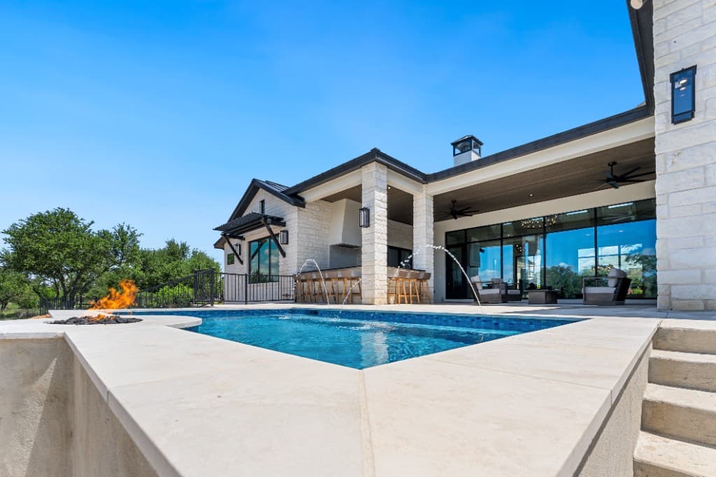 Low-angle view of a custom pool, fire pit, and outdoor kitchen